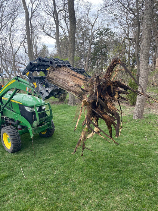 Operator using Stinger compact tractor grapple bucket to move branches – reliable grapple built for strength, control, and precision.