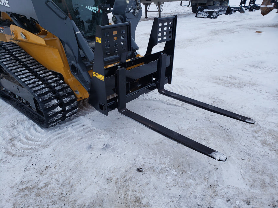 Stinger heavy-duty skid steer pallet forks transporting crates and supplies – built for power and long-lasting durability.