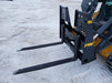 Skid steer pallet forks by Stinger lifting pallet of bricks – perfect attachment for construction, warehouse, and agricultural work.