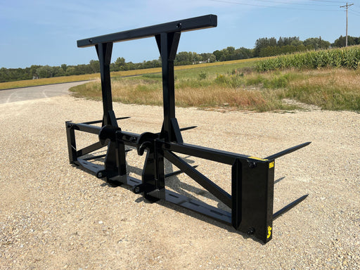 Heavy-duty Bale Spear Series 5XD mounted on a tractor lifting a large round hay bale in an open field.