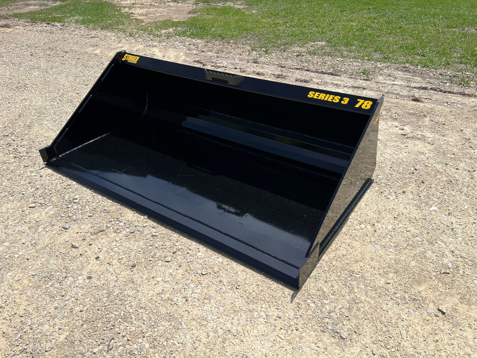 Operator using Stinger Series 3 skid steer material bucket to move dirt – reliable attachment for excavation, grading, and site cleanup.