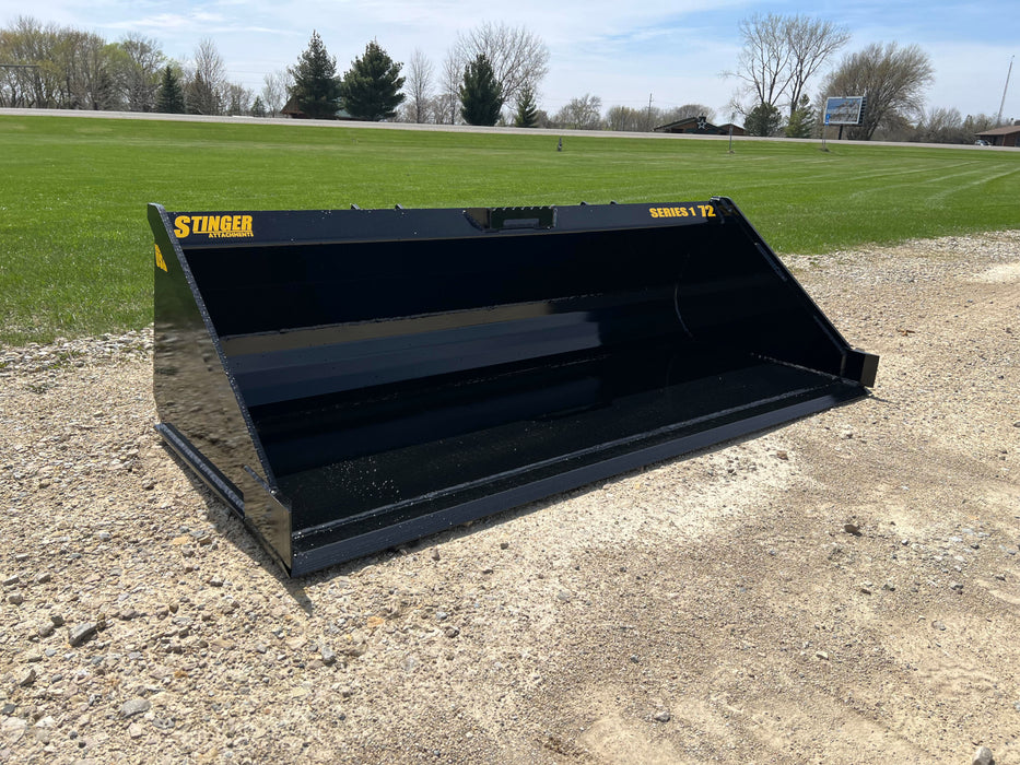 Stinger Series 1 skid steer material bucket loading soil on construction site – heavy-duty attachment built for efficient material handling.