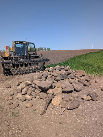 Heavy-duty tractor rock bucket mounted on a utility tractor during a landscaping and excavation project.