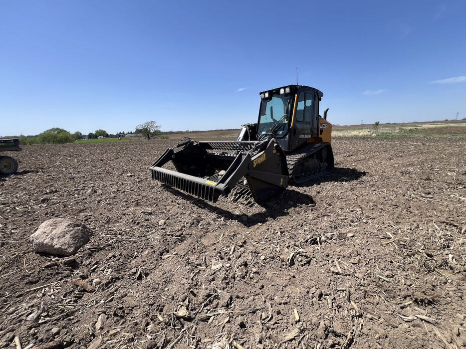 Heavy-duty skid steer rock reel by Stinger handling mixed debris – ideal tool for landscaping, agriculture, and construction projects.