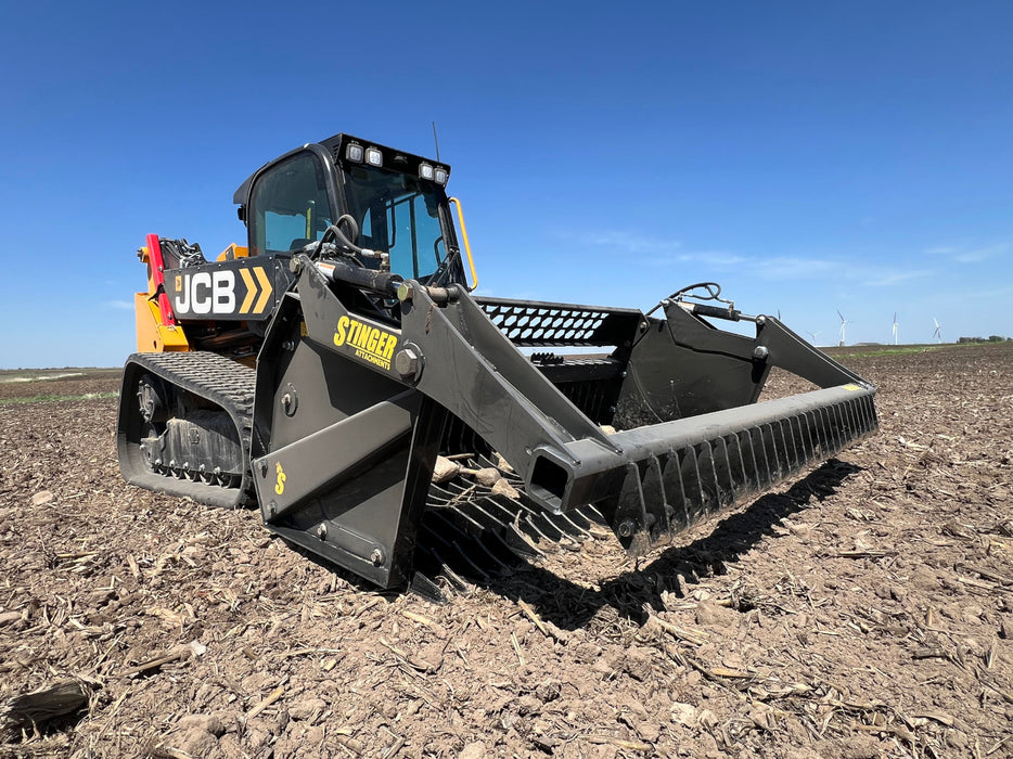 Tractor rock bucket in action, scooping stones and separating fine soil for land preparation.