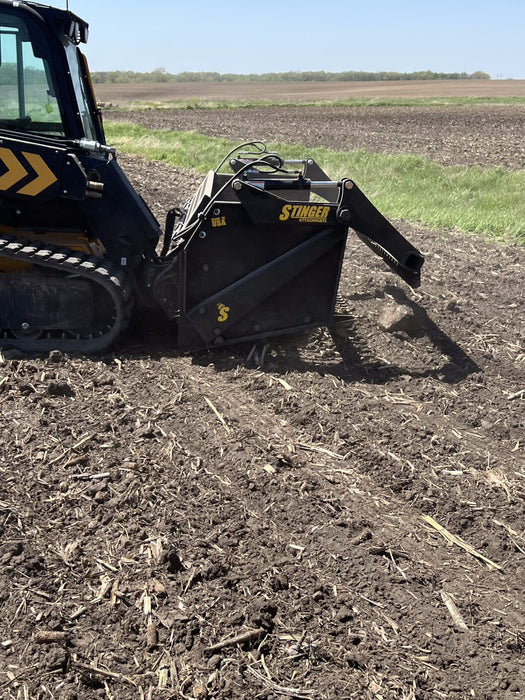 Side profile of heavy-duty skid steer rock reel operating on rocky terrain – built to handle demanding land clearing tasks.