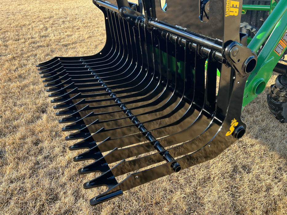 Operator using compact skid steer grapple bucket to move rocks – reliable attachment ideal for landscaping, construction, and cleanup work.