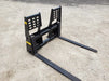 Operator maneuvering skid steer pallet forks to load truck – efficient and rugged design for smooth lifting operations.