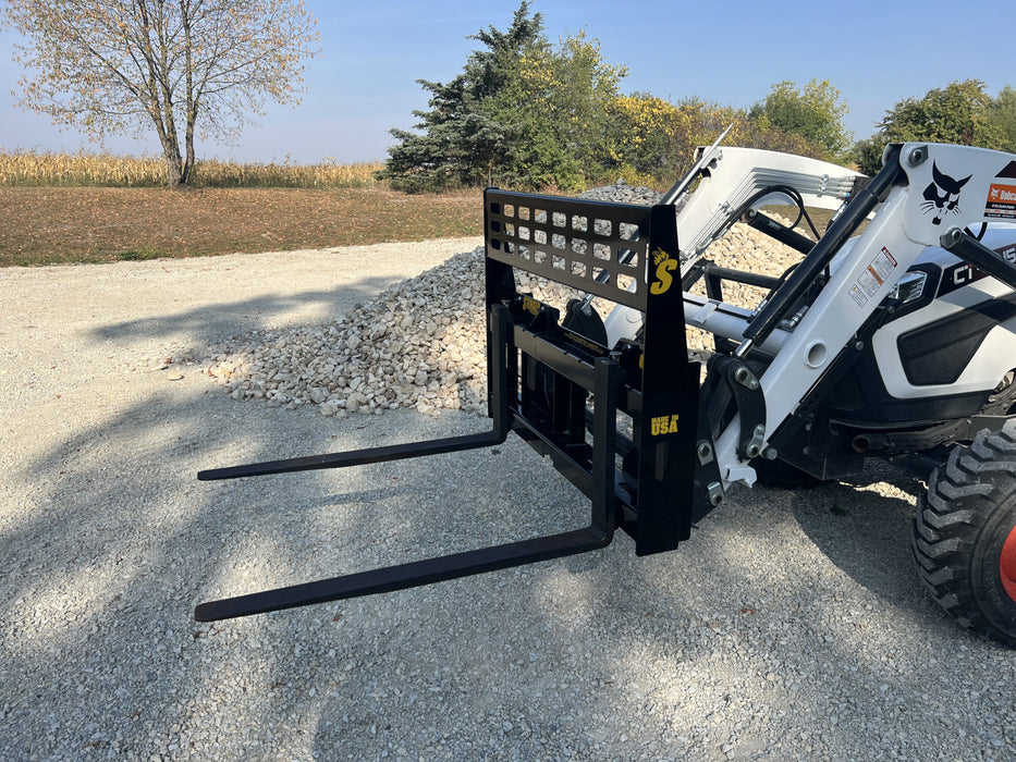 Operator using Stinger skid steer pallet fork to lift construction materials – heavy-duty design ensures stability and precision.