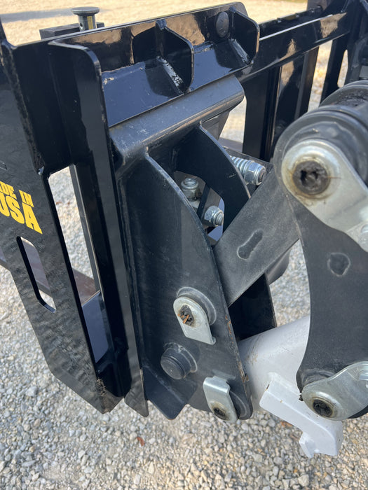 Skid steer pallet fork by Stinger transporting crates across worksite – rugged and versatile attachment ideal for agricultural and industrial use.