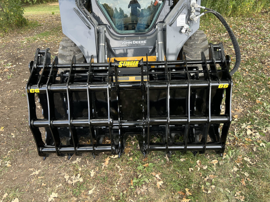 Utility tractor equipped with a Clam Grapple bucket handling brush, logs, and large rocks with ease.