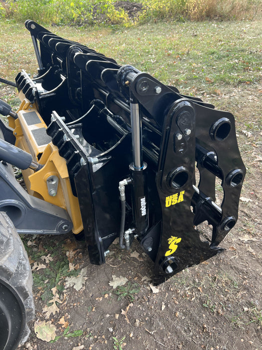 Industrial-grade Clam Grapple resting on gravel ground, highlighting heavy-duty design and robust hinge system.