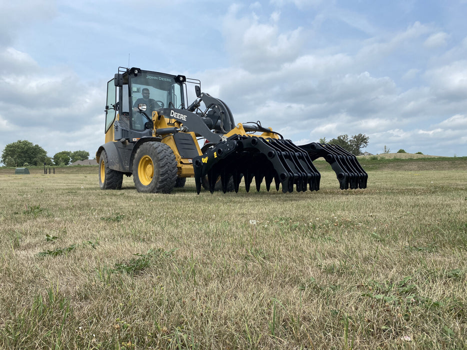 Side view of the Stinger tractor grapple bucket highlighting durable steel tines and hydraulic cylinders.