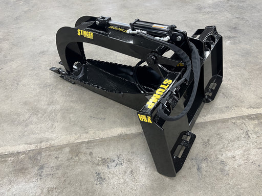 Heavy-duty Stump Grapple Bucket attached to a skid steer removing large tree stumps and roots from the ground.