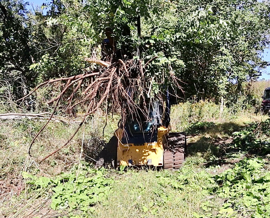 Durable skid steer tree puller gripping brush pile – rugged construction ideal for clearing fence lines and overgrown areas.