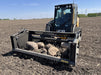 Skid steer rock reel by Stinger sorting large stones on construction site – heavy-duty grapple attachment built for power and reliability.