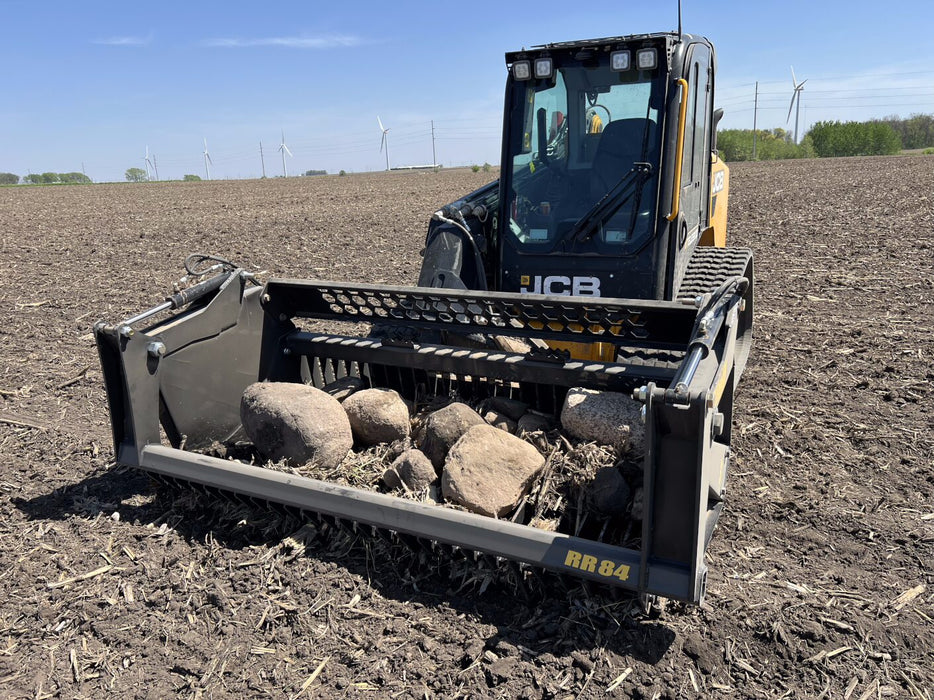 Skid steer rock reel by Stinger sorting large stones on construction site – heavy-duty grapple attachment built for power and reliability.