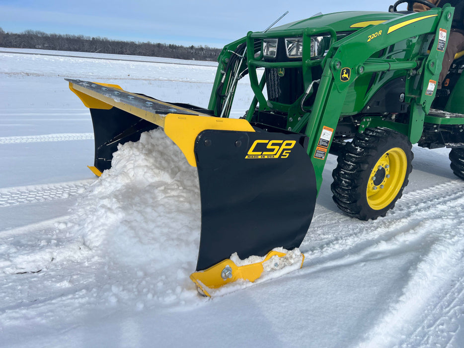 Operator using compact skid steer snow pusher to clear snow from farm road – efficient attachment for fast and smooth operation.