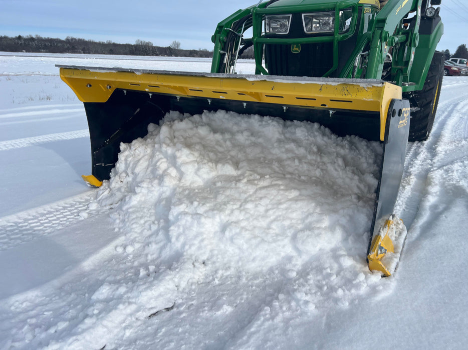 Compact skid steer snow pusher clearing heavy snow from driveway – durable attachment built for efficient winter maintenance.