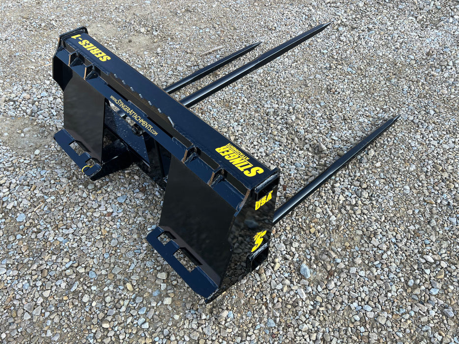 Farmer using Stinger Series 1 bale spear to move hay bale into barn – ideal for livestock feeding and daily agricultural operations.