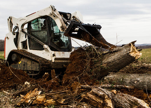 Loflin Fabrication skid steer stump bucket digging and prying out deep roots – heavy-duty attachment built for powerful stump removal and land preparation.