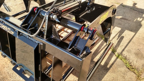 Stinger skid steer grapple bucket in action gripping compacted manure – efficient attachment for farm and ranch maintenance.