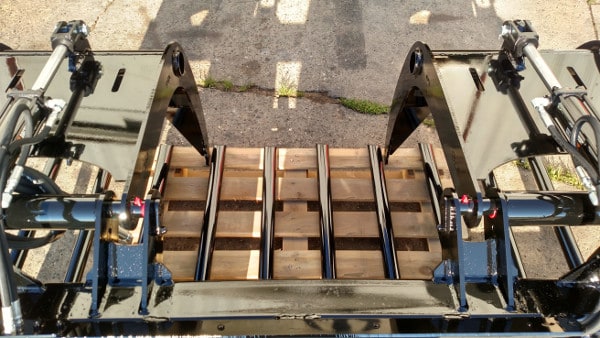 Heavy-duty skid steer grapple bucket by Stinger Attachments holding mixed debris – perfect for agricultural and industrial cleanup tasks.